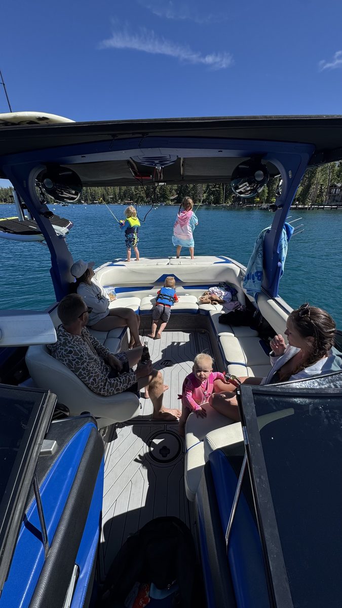 Children and adults aboard a boat on a lake.