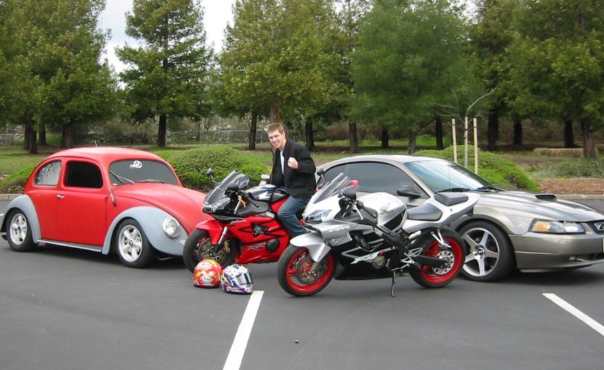 A red and silver Beetle, two sportbikes and a
                                   Mustang parked together in a car park.