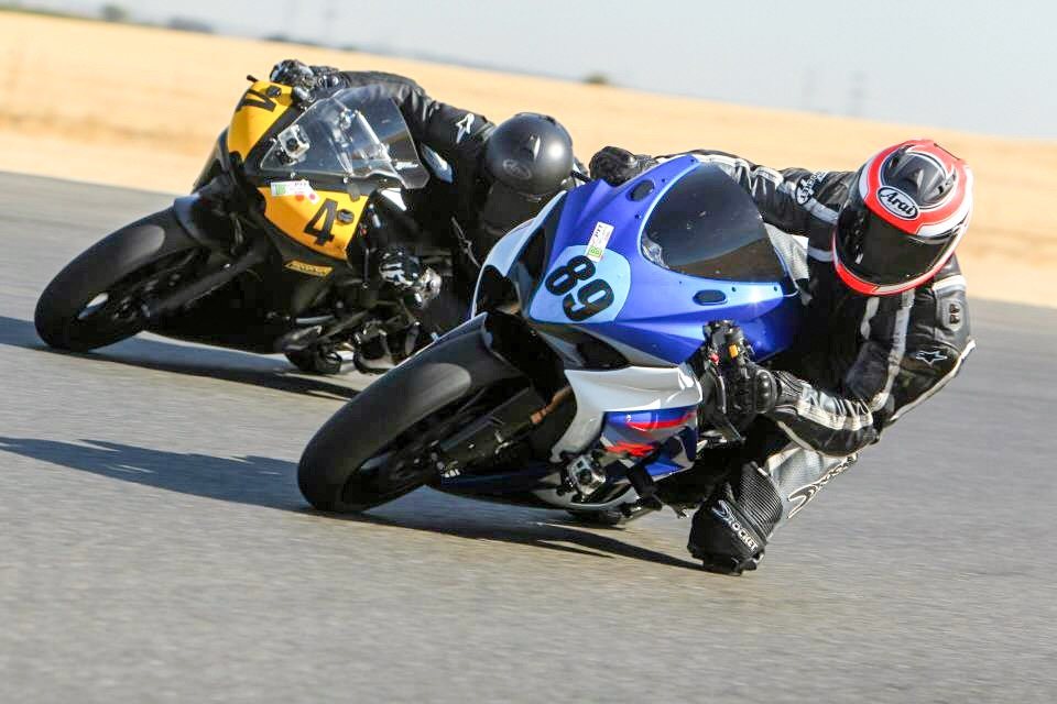 Two sportbikes leaned hard through a corner on
                                   a race track.